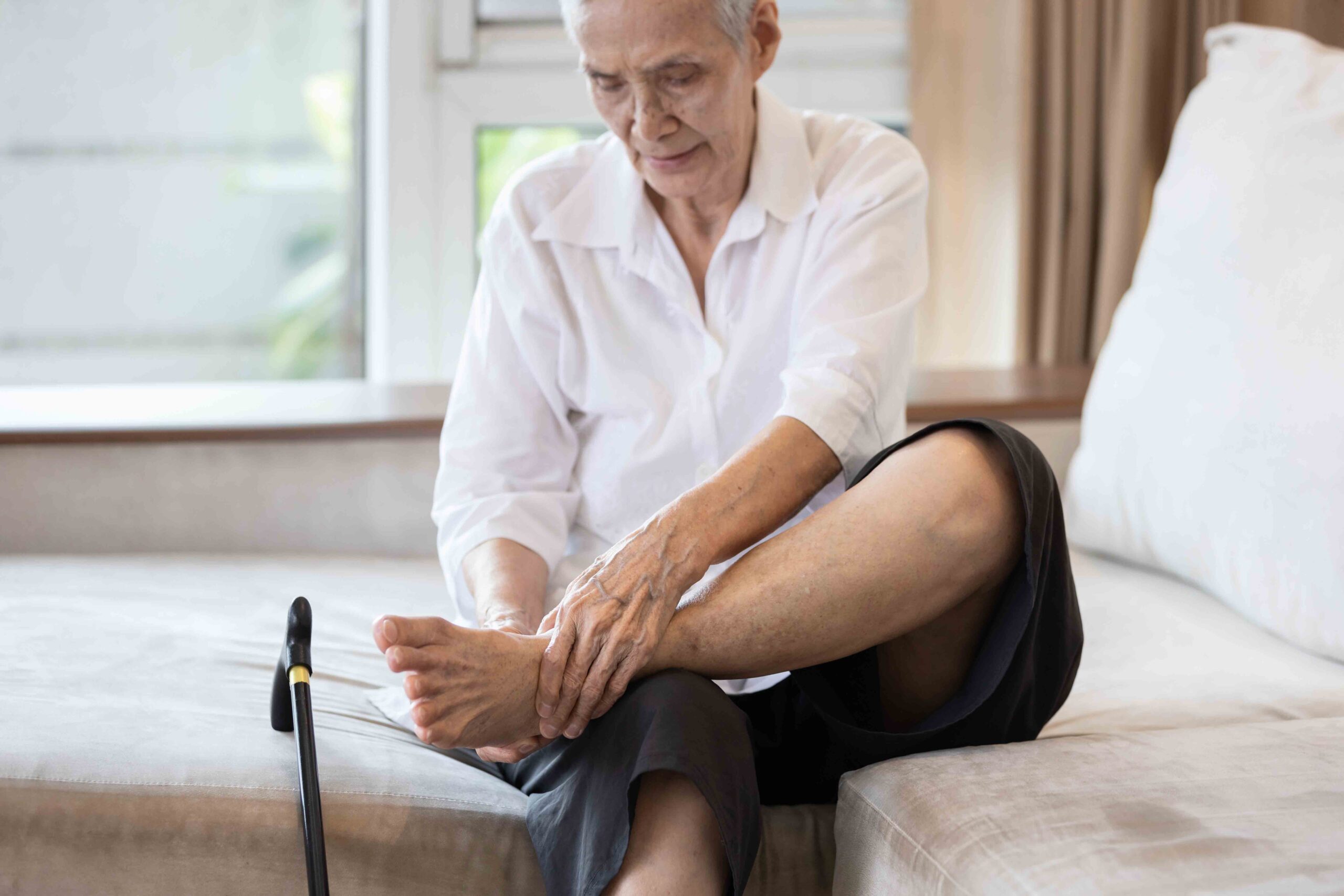 An elderly individual inspecting their foot, highlighting the importance of diabetic foot screening and podiatry care.